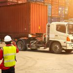 A foreman directing a truck with a container truck